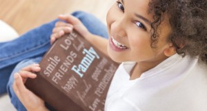 Mixed race girl holds family photos  Credit: Shutterstock.com