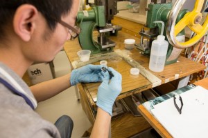 Doctoral student KeLiang Wang places a graphene-coated electrode into a button cell to make a supercapacitor.  Credit: Emily Weber