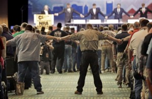 National Rifle Association members hold hands during the opening prayer at the annual meeting of members at the NRA convention Saturday, April 11, 2015, in Nashville, Tenn. Credit: AP Photo/Mark Humphrey