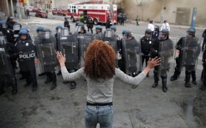 A lone women stands off police durring recent Baltimore demonstrations. Credit: Telegraph (U.K.)