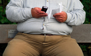 AGY01X Obese man sending a text message from mobile phone, Surbiton, UK.. Image shot 2007. Exact date unknown.