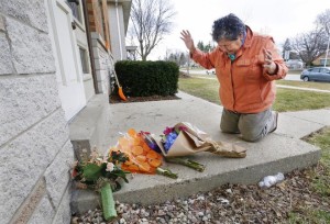 Elena Yrlas of Milwaukee says a prayer after placing flowers at the apartment doorstep of her friend and colleague Mai K. Vue, 32, who was shot and killed there on Sunday. Credit: Journal-Sentinel