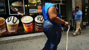 A woman walks by a sign advertising sugary drinks in a Brooklyn, USA, neighborhood Credit: AFP/Spencer Platt