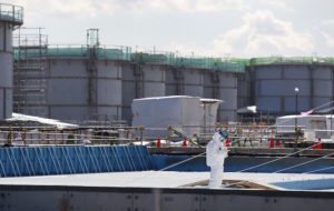 A worker in front of the tritium water storage tanks Credit: Toru Hanai/AP 