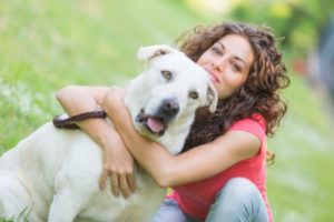 Woman hugging her dog, who is not enjoying it. Credit: www.care2.com