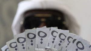 A Saudi man poses with Saudi riyal banknotes. Credit: Faisal Al Nasser / Reuters 