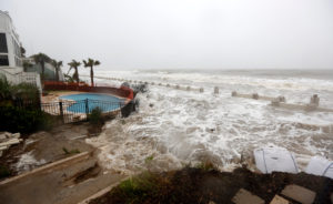 Waves crashing over an experimental sea wall built to protect homes during high tide in Isle of Palms, S.C., last year.  Credit Mic Smith/Associated Press