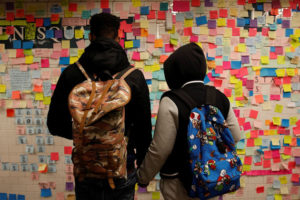 People holds hands looking at post-election Post-it notes  pasted along a tiled walk at Union Square subway station in New York U.S., November 14, 2016.  Credit:Reuters/Shannon Stapleton